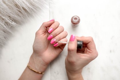 person applying glittery pink nail polish