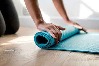 a woman rolling up a yoga mat after exercising