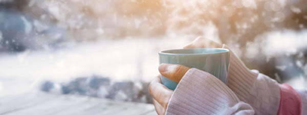 woman holding hot mug in snow