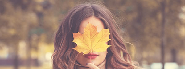 A woman holding a leaf in front of her face