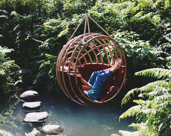 Woman in a wooden swing above a pond