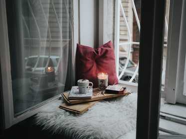 A candle, mug and books in a windowsill