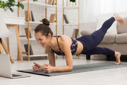 Woman doing online yoga workout in living room