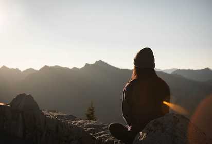 A lady sitting on a hill and meditating